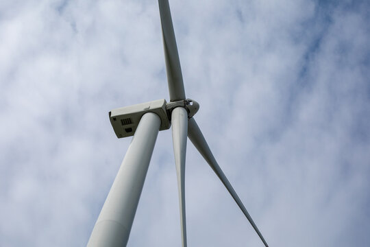 Towering wind turbine slices the sky, capturing Zephyr's whispers, celebrating World Energy Conservation Day and Arbor Day's green promise