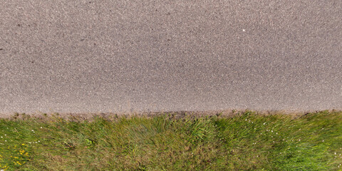 top view of textured asphalt road with median strip and grass lawn