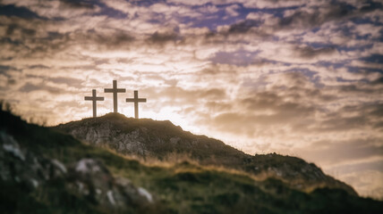 Obraz premium Christianity symbolized by three crosses on a hill at sunset with colorful clouds overhead
