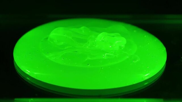 Glowing Green Slime Pours and Pools on a Black Surface in Studio