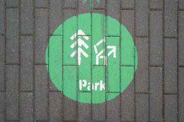 green park direction sign painted on brick pathway indicates route to nearby park with arrow and...