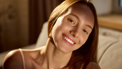 Smiling woman with natural glow in soft morning light. Concept of inner peace, emotional wellbeing, beauty campaign for radiant skin products, clean beauty and minimal makeup