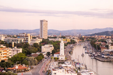 Lghthouse in the port of the Italian city of Rimini top view. Street traffic in port. Hotels and houses building street