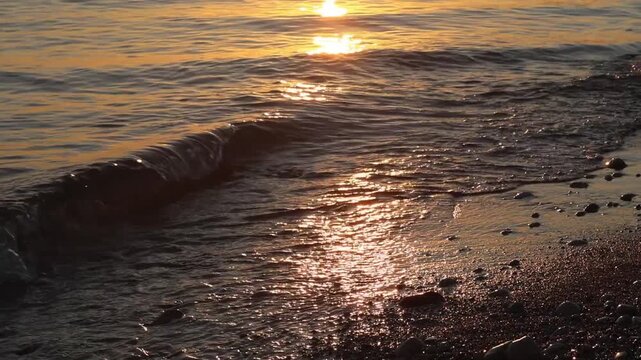 Warm sandy sea shore as waves gently roll in. Carefree summer moment of people walking barefoot along a tropical beach at sunset. A serene coastal scene capturing leisure, travel, and relaxation