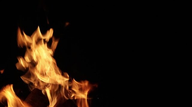Close-up of a glowing campfire burning brightly in the dark night. Abstract flames over crackling wood, radiating heat and vivid orange-red light. A dynamic and flammable background
