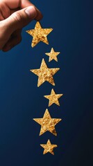 Hand holding glittering gold stars against dark blue background