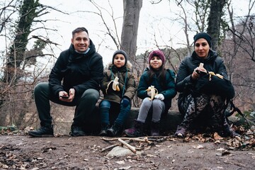 Fototapeta premium Family hiking eating bananas during winter nature break