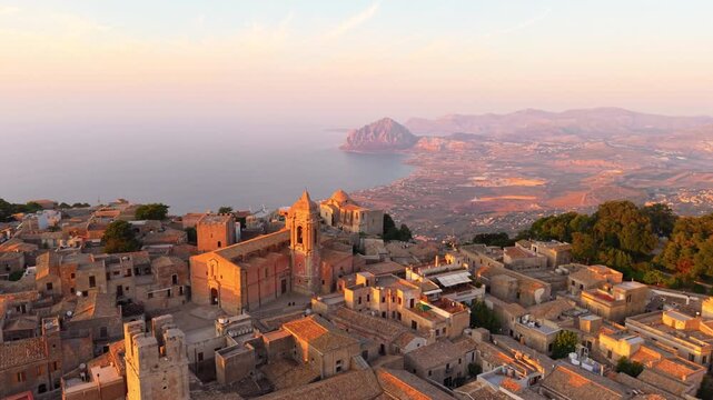 Erice Village With Ancient Church Overlooking The Mount Cofano And Calm Sea At Sunset In Sicily, Italy. - aerial shot
