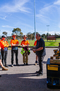 man giving tool demonstration to young trade apprentices standing outside