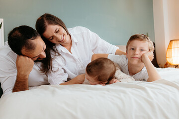 Fototapeta premium Happy family relaxing together on bed in bedroom