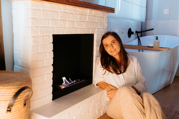 Woman relaxing by modern fireplace in bathroom