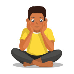 African man feeling sad, upset, and crying sitting on the floor cross legged with hands on his cheek