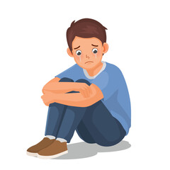 Man feeling sad, upset, and crying sitting on the floor hugging his legs