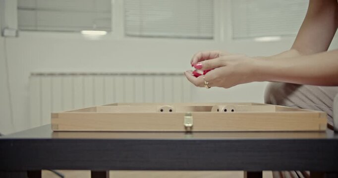 A close-up view of hands moving backgammon checkers and dice, producing clear and engaging sounds. This video highlights the tactile and auditory experience of playing a classic board game at home.