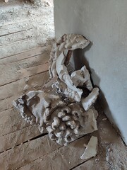 Broken plaster ornament on dusty wooden floor, vintage architecture decay detail