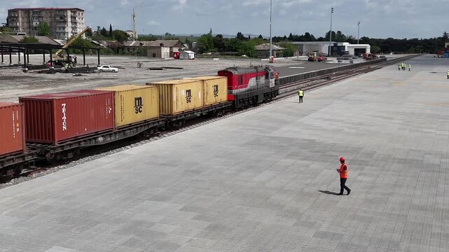 Aerial 4K drone footage of reach stackers handling shipping containers at a modern container terminal. Industrial port operations, cargo loading and unloading, logistics and transportation process in 