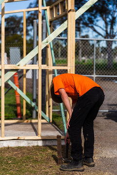 young worker in orange workwear by ticket booth slab and frame