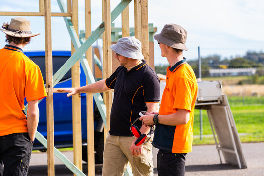 Trade instructor teaching students during hands on learning course building frame of ticket booth