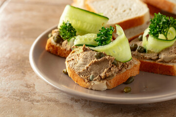 Open sandwiches with pate, cucumber, capers, and parsley.