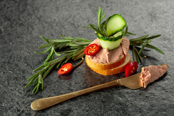 Bread slices with pate, cucumber, red pepper, and rosemary.