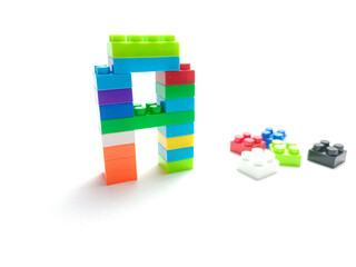 Naklejka premium Childrens building blocks construction, red. multi-colored children's plastic constructor on a white isolated background. Kids playing learning ABC alphabet 