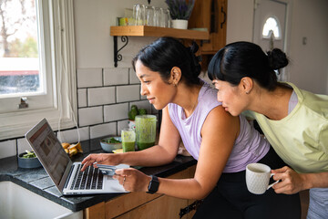 Young female couple online shopping together from home