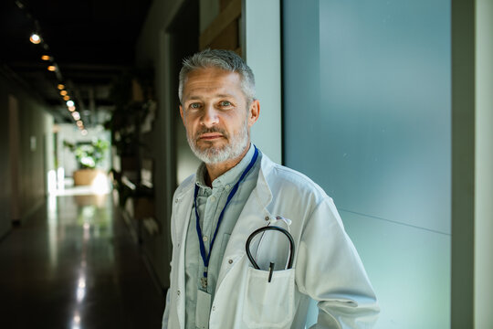 Mature doctor standing in hospital hallway