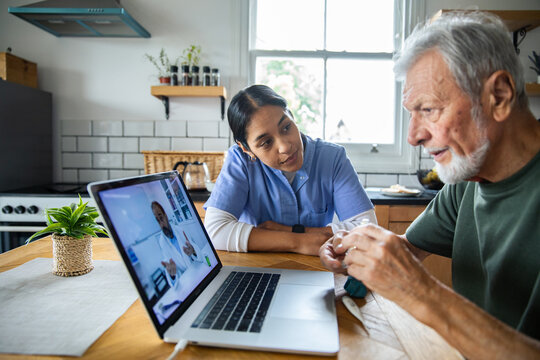 Senior man and caregiver on video call with doctor
