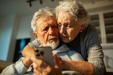 Concerned senior couple looking at smartphone