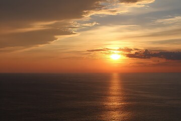 Fototapeta premium Dramatic Sunset Over Calm Ocean Waters With Golden Hues and Cloudscape Reflections