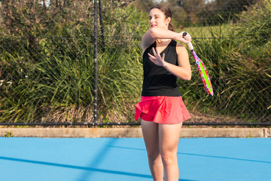 young woman playing tennis on a blue outdoor court