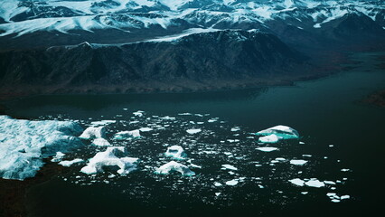 Breathtaking icebergs drift gently on the still waters of a remote Arctic fjord, surrounded by rugged mountains and a twilight sky, showcasing the serene beauty of natures wonders. © icetray