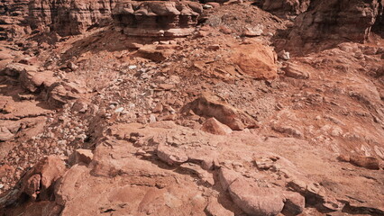 Vast stretches of rocky ground dominate the scene, revealing a palette of earthy tones under a clear blue sky, inviting adventure and exploration in this remote location at midday.