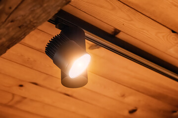 Modern track light providing warm illumination for a wooden ceiling, highlighting contemporary...