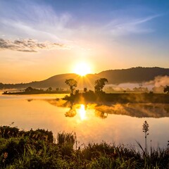Sunrise over tranquil lake with mist and mountain
