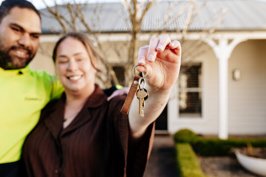 Mixed ethnicity couple showing keys of their new home