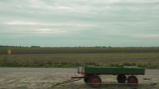 Farmland with wind turbines. Footage of flat farmland with wind turbines and distant buildings, filmed through the train window.