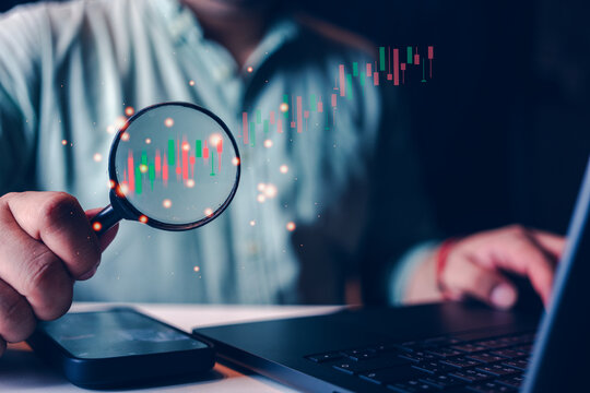 Stock market for analysis, technical graph, indicator, candle stick, Businessman or trader hand holding magnifier glass with virtual stock market chart, Business investment earning income concept.