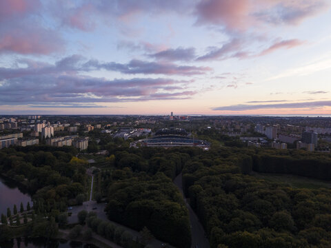 Aerial view of a vibrant cityscape with the lush green canopy and malmo stadium under a pastel sky at sunset, Malmo, Scania County, Sweden.