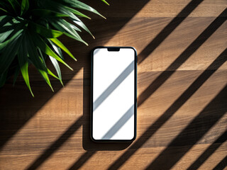 Modern smartphone with blank screen resting on a wooden surface with dramatic striped sunlight and shadows