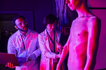 Scientists conduct research on a tall alien being in a high tech laboratory setting