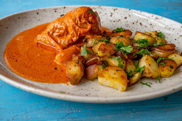 Fried potato, stuffed pepper with minced meat and tomato sauce on plate