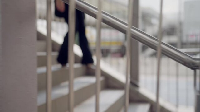 Blurred abstract image of businesswoman climbing stairs in city walkway. Concept of growth, personal journey, development, and forward movement in career.