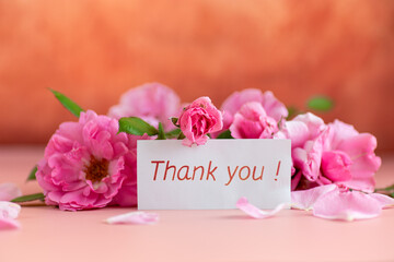 Delicate pink roses and a card with the word thank you
