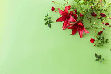 Two large red lilies with red roses on green background