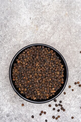 Black peppercorns on white stone table background