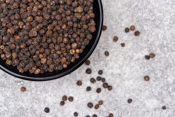 Black peppercorns on white stone table  background