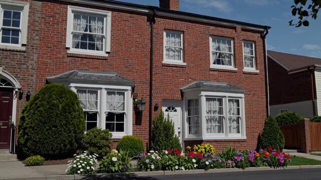 Charming brick house with colorful garden, captured from a street-level angle. Ideal for a real estate video showcasing suburban living.