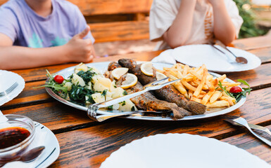 Mediterranean culinary. Istrian grilled fish with potatoes and vegetables served outdoors in Croatian restaurant. People enjoying Grilled Sea Bream with a glass of beer at summer vacation