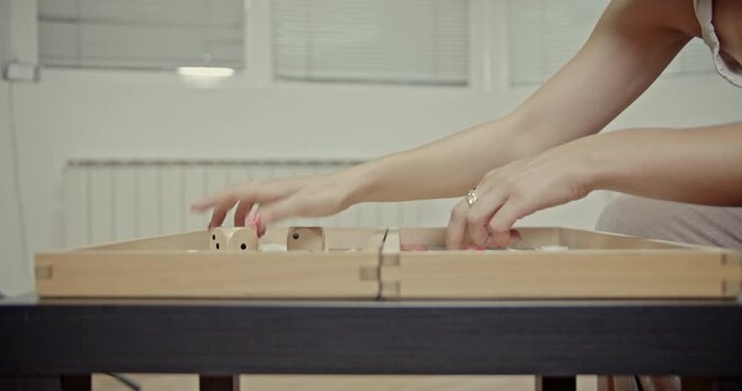 Engaging close-up footage captures hands expertly rolling dice and strategically moving checkers on a backgammon board. Hear the distinct sounds of game play.